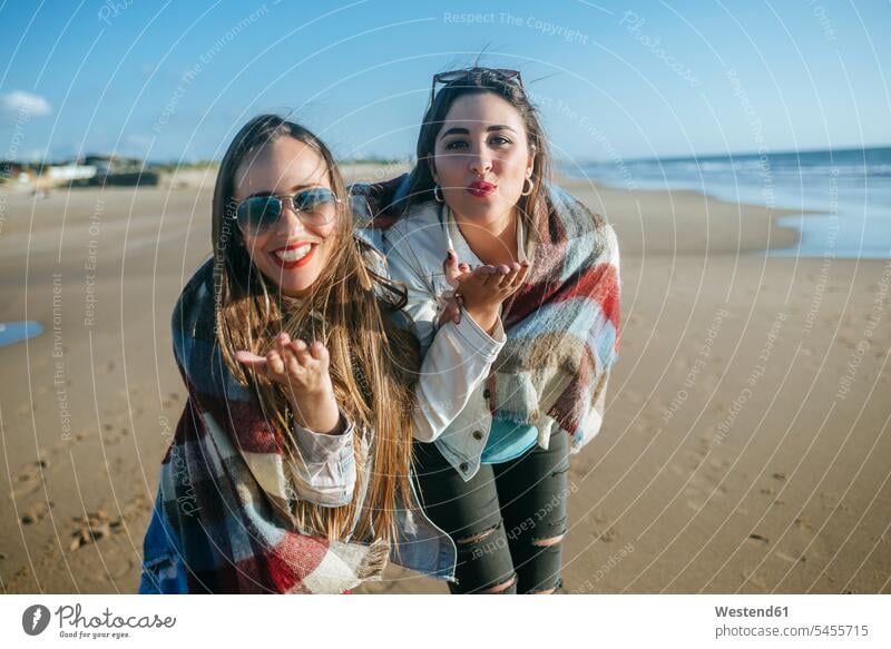 Porträt von zwei jungen Frauen am Strand, die Küsse blasen Beach Straende Strände Beaches Luftkuss Kuss zuwerfen einen Kuss zuwerfen Freundinnen Freunde