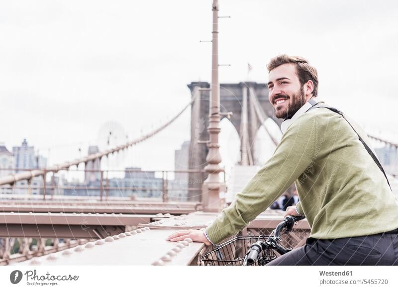 USA, New York City, lächelnder Mann auf dem Fahrrad auf der Brooklyn Bridge Brücke Bruecken Brücken Bikes Fahrräder Räder Rad New York State Männer männlich