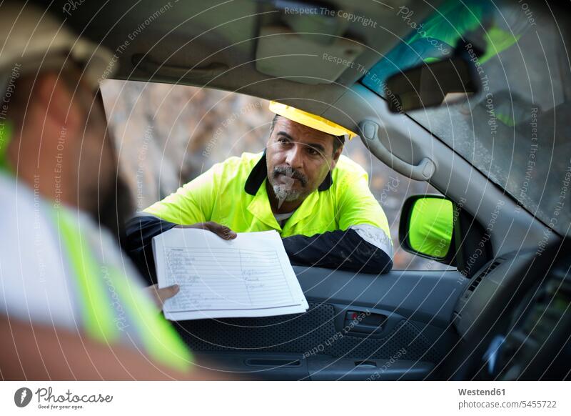 Arbeiter übergibt Dokumente an im Auto sitzenden Kollegen Schutzkleidung Schutzbekleidung Kiesgrube Schottergrube Kiesgruben Schottergruben Leuchtweste