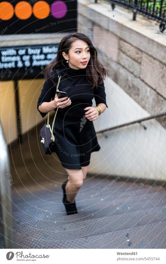 USA, New York City, Manhattan, junge Frau in Schwarz gekleidet geht die Treppe hinauf weiblich Frauen Erwachsener erwachsen Mensch Menschen Leute People