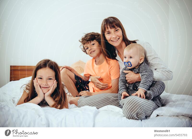 Glückliche Mutter mit ihren drei Kindern im Bett Portrait Porträts Portraits Mami Mutti Mütter Mama Betten lächeln Familie Familien Eltern Mensch Menschen Leute