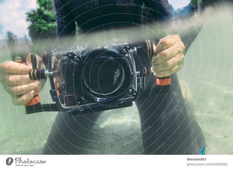 Mann hält Unterwasser-DSLR-Kamerakoffer in einem See Taucher Kameras tauchen Männer männlich Fotoapparat Fotokamera Wassersport Sport Erwachsener erwachsen