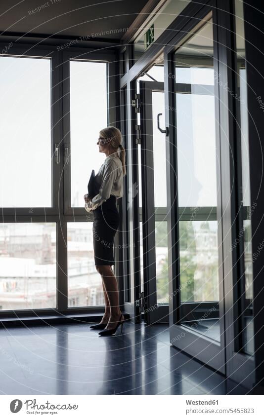 Geschäftsfrau im Amt, die aus dem Fenster schaut stehen stehend steht Geschäftsfrauen Businesswomen Businessfrauen Businesswoman Geschäftsleute