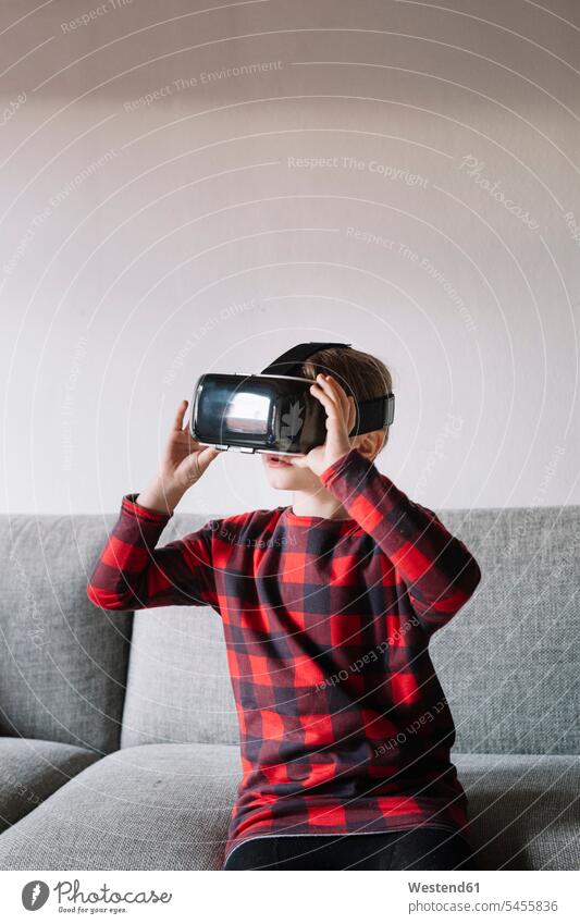 Mädchen sitzt auf der Couch im Wohnzimmer und benutzt eine Virtual-Reality-Brille Sofa Couches Liege Sofas benutzen benützen Virtual Reality Brille
