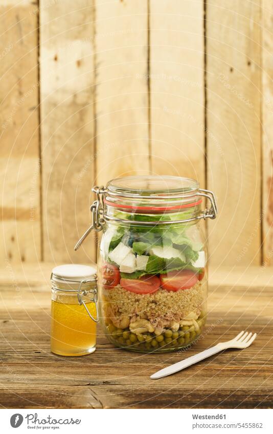 Einmachglas für gemischten Salat mit Erbsen, Thunfisch, Couscous, Tomaten, Thunfisch, Feta und Glas Vinaigrette-Dressing selbstgemacht selbstgemachte