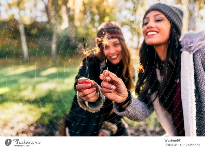 Zwei glückliche Frauen halten Wunderkerzen in einem herbstlichen Wald Forst Wälder Herbst Glück glücklich sein glücklichsein schön weiblich Freundinnen