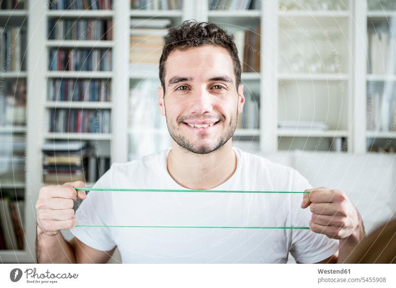 Porträt eines Mannes, der zu Hause ein Fitnessband benutzt Zuhause daheim lächeln fit Gesundheit gesund Männer männlich sportlich Sport Erwachsener erwachsen