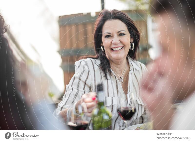 Lächelnde ältere Frau beim Familienessen im Garten Wein Weine Freunde Rotwein Rotweine lächeln feiern Gruppe Gruppe von Menschen Menschengruppe Alkohol