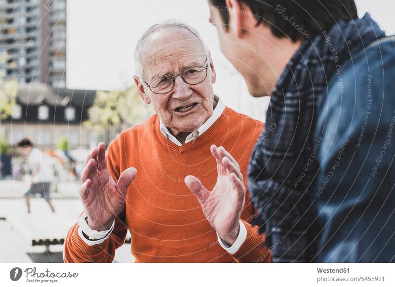 Älterer Mann im Gespräch mit erwachsenem Enkel im Freien Enkelsöhne Enkelsohn sprechen reden Großvater Opa Großpapa Großpapas Opas Opi Großväter Opis Enkelkind