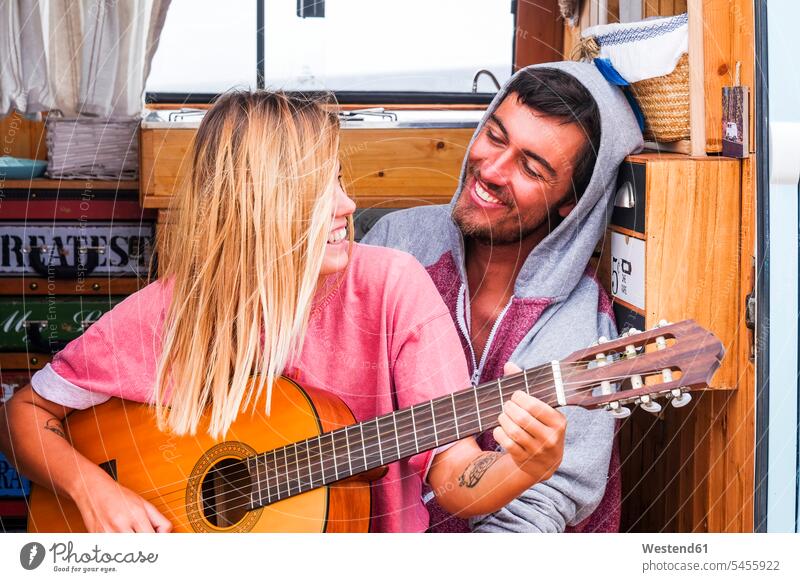 Junges gitarrenverliebtes Paar in einem Lieferwagen Campingbus Gitarre Gitarren Pärchen Paare Partnerschaft Kleinbus Kleinbusse Kraftfahrzeug Verkehrsmittel KFZ