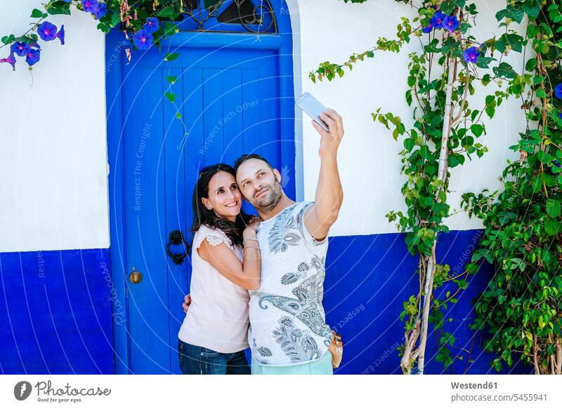 Marokko, Tanger, Paar macht Selfie mit Smartphone vor blauer Tür Türen iPhone Smartphones Selfies Pärchen Paare Partnerschaft blaues Handy Mobiltelefon Handies