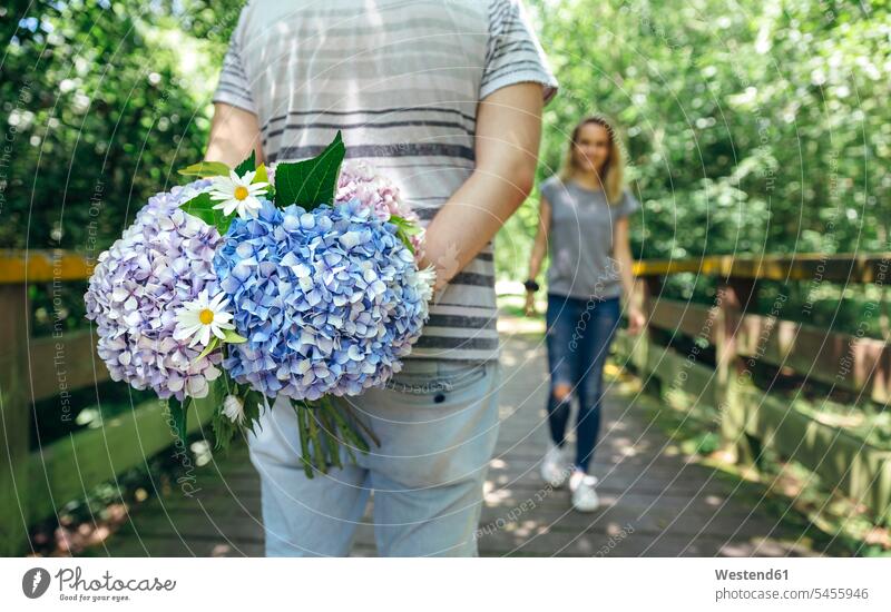 Mann hält hinter seinem Rücken einen Strauß Hortensien, um seine Freundin zu überraschen Blumenstrauß Bouquet Blumenstrauss Blumensträusse Blumensträuße Weg