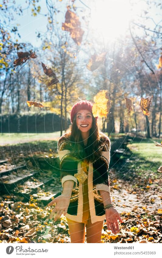 Porträt einer schönen glücklichen Frau, die sich mit Blättern in einem herbstlichen Wald vergnügt Forst Wälder Glück glücklich sein glücklichsein Blatt Blaetter