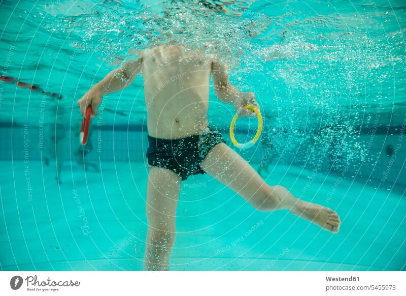 Junge hält zwei Sprungringe im Schwimmbad unter Wasser Schwimmbaeder Schwimmbäder schwimmen Buben Knabe Jungen Knaben männlich Unterwasser Unterwasseraufnahme