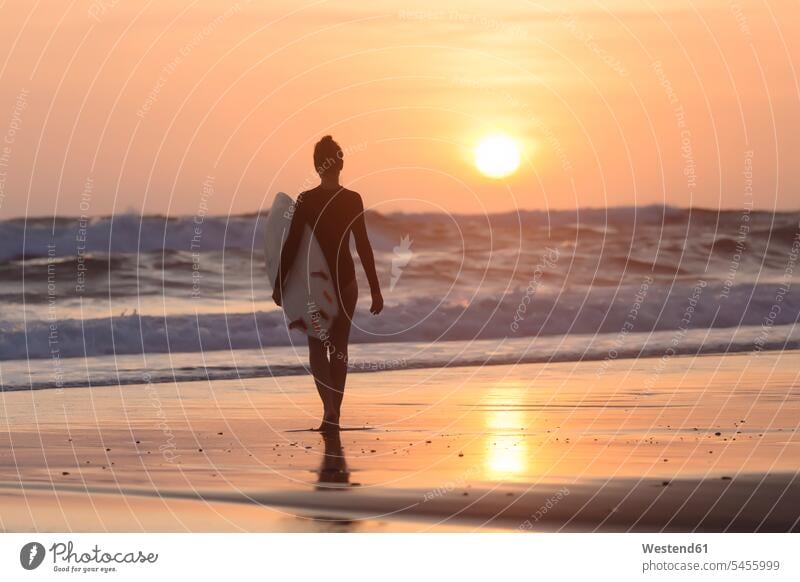 Indonesien, Bali, junge Frau mit Surfbrett bei Sonnenuntergang gehen gehend geht Freizeit Muße Surfbretter surfboard surfboards weiblich Frauen Abend abends