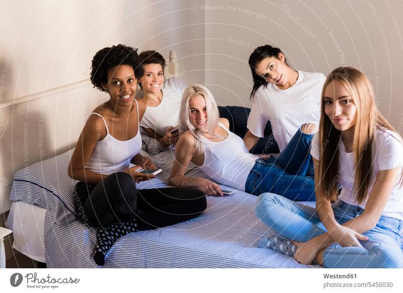 Porträt von Freundinnen mit Mobiltelefonen im Schlafzimmer Zuhause zu Hause daheim glücklich Glück glücklich sein glücklichsein Bett Betten Handy Handies Handys