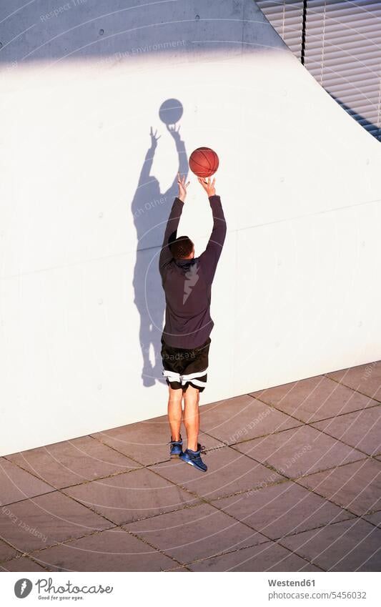 Junger Mann spielt Basketball in der Stadt Männer männlich werfen Wurf trainieren Basketbaelle Basketbälle Erwachsener erwachsen Mensch Menschen Leute People