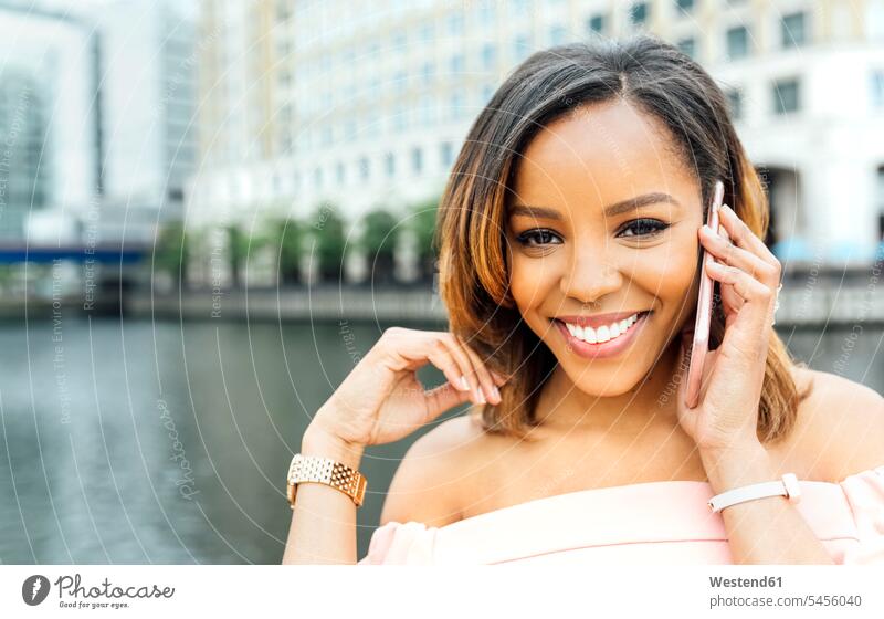 Porträt einer lächelnden Frau beim Telefonieren in der Stadt telefonieren anrufen Anruf telephonieren Handy Mobiltelefon Handies Handys Mobiltelefone weiblich