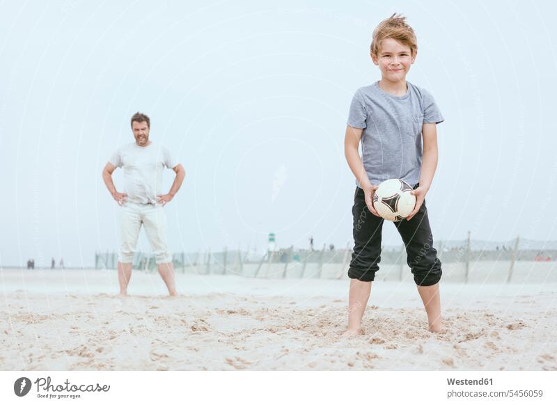 Porträt eines lächelnden kleinen Jungen, der mit seinem Vater am Strand spielt Papas Väter Vati Vatis Papis Beach Straende Strände Beaches Sohn Söhne Eltern