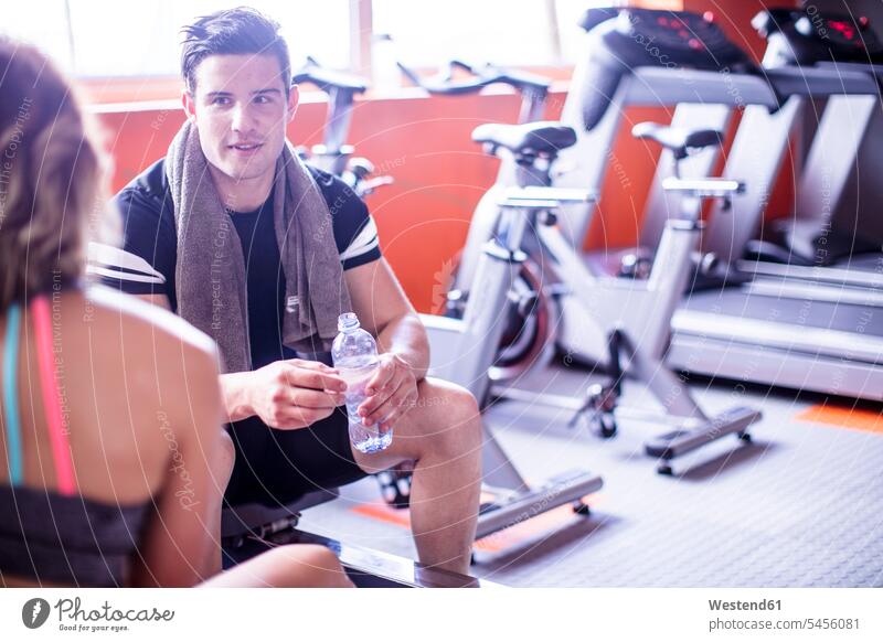 Junger Mann und Frau machen eine Erfrischungspause im Fitnessstudio trainieren Fitnessclubs Fitnessstudios Turnhalle Pause fit Gesundheit gesund Sport Wasser