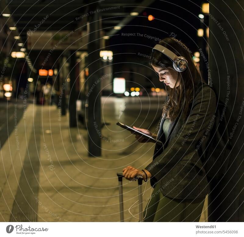 Junge Frau mit Kopfhörer und Tablette wartet nachts am Bahnhof Nacht weiblich Frauen Erwachsener erwachsen Mensch Menschen Leute People Personen warten