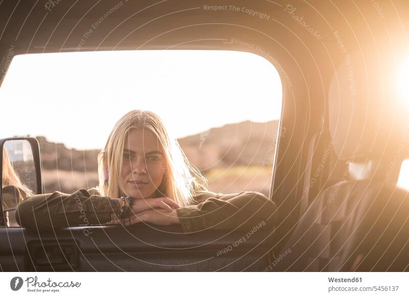 Porträt einer jungen Frau, die am Autofenster lehnt und nach innen schaut weiblich Frauen Portrait Porträts Portraits Wagen PKWs Automobil Autos Erwachsener
