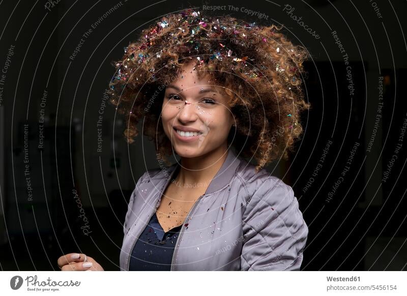 Porträt einer lachenden Frau mit Konfetti auf dem Haar vor dunklem Hintergrund Confetti Haare Portrait Porträts Portraits weiblich Frauen Mensch Menschen Leute