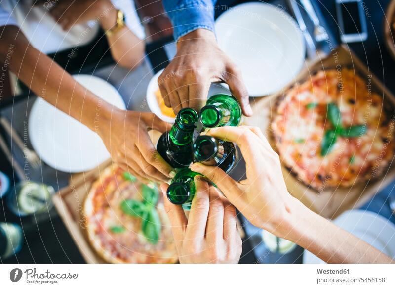 Gruppe von Freunden bei Pizza und Bier zu Hause Tisch Tische Pizzen essen essend anstoßen zuprosten anstossen Essen Food Food and Drink Lebensmittel
