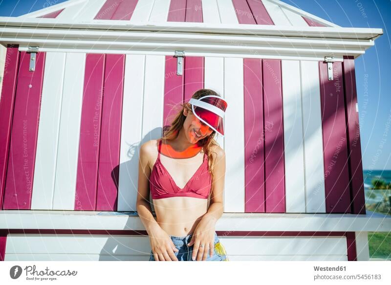 Glückliche junge Frau mit Bikini und Sonnenblende vor dem Kiosk lächeln weiblich Frauen Erwachsener erwachsen Mensch Menschen Leute People Personen Spanien