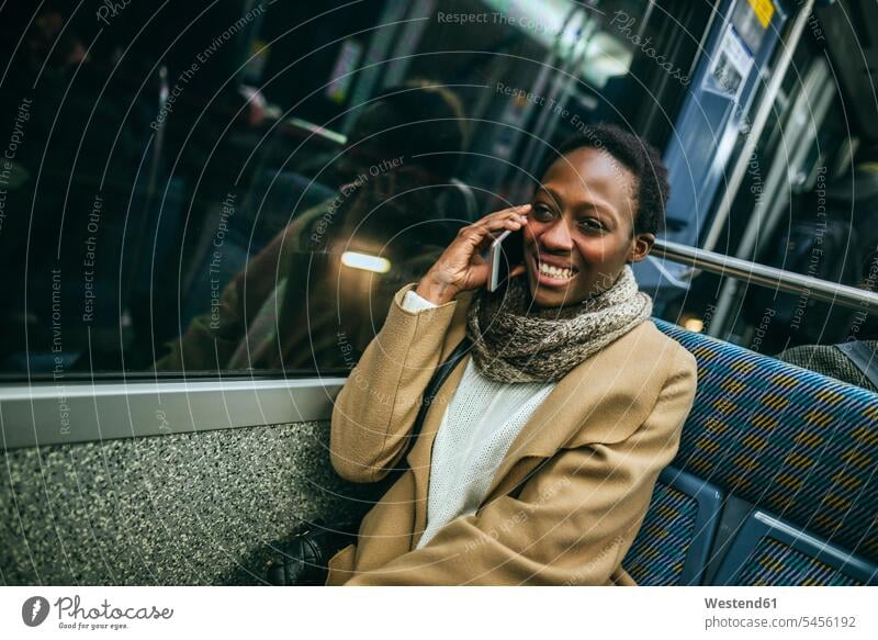 Porträt einer lächelnden jungen Frau am Telefon in der U-Bahn Portrait Porträts Portraits telefonieren anrufen Anruf telephonieren weiblich Frauen