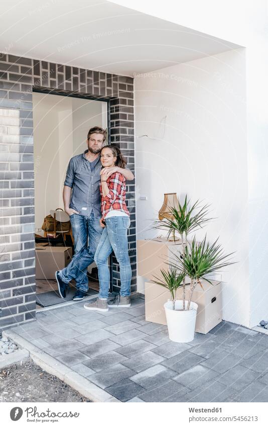 Glückliches Paar steht in der Tür seines neuen Zuhauses bauen Eigentum Wohnung wohnen Wohnungen Eigentümer Pärchen Paare Partnerschaft Umzug umziehen Wohnen