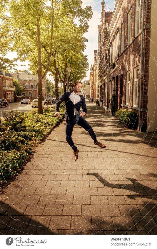 Niederlande, Venlo, glücklicher Geschäftsmann springt auf den Bürgersteig springen hüpfen Businessmann Businessmänner Geschäftsmänner Stadt staedtisch städtisch
