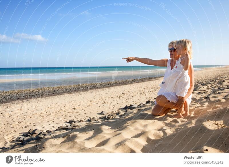 Spanien, Fuerteventura, Mutter mit Tochter am Strand Töchter Mami Mutti Mütter Mama zeigen mit dem Finger zeigen deuten Beach Straende Strände Beaches Kind