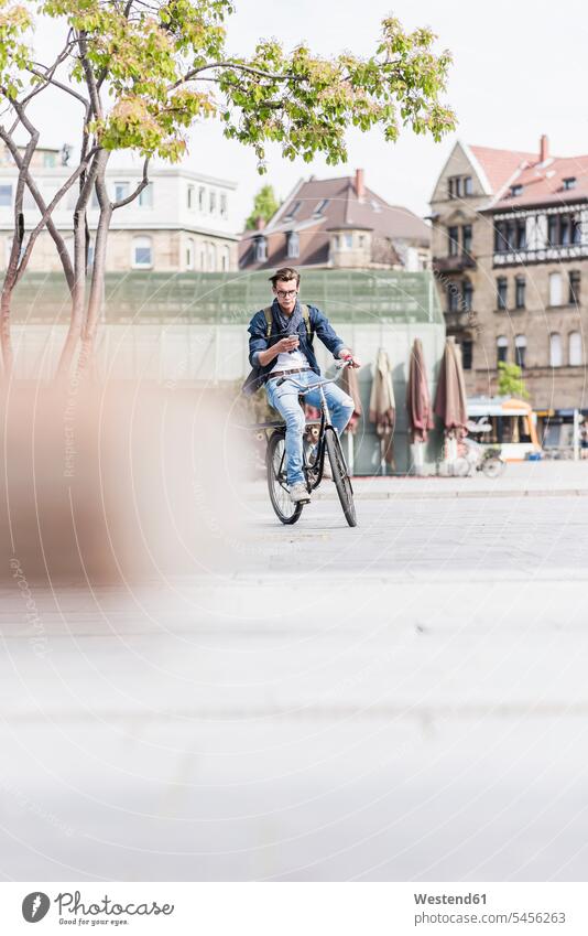 Junger Mann mit Fahrrad in der Stadt mit Handy Männer männlich fahren Bikes Fahrräder Räder Rad Mobiltelefon Handies Handys Mobiltelefone Erwachsener erwachsen