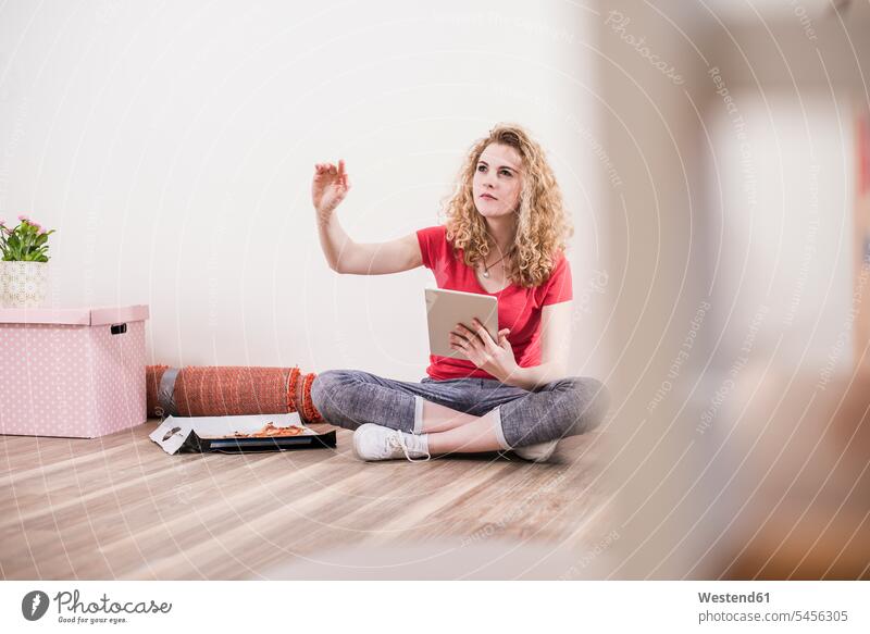 Junge Frau in neuer Wohnung mit Tablette auf dem Boden sitzend wohnen Wohnungen Tablet Computer Tablet-PC Tablet PC iPad Tablet-Computer weiblich Frauen Wohnen