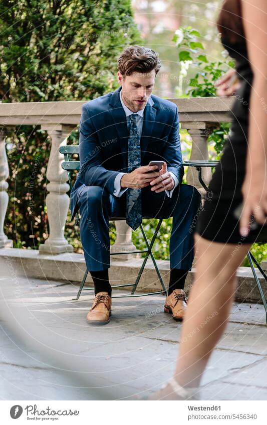 Geschäftsmann in Manhattan sitzt auf Gartenstuhl mit Smartphone lesen Lektüre Handy Mobiltelefon Handies Handys Mobiltelefone Gartenstühle Gartenstuehle sitzen