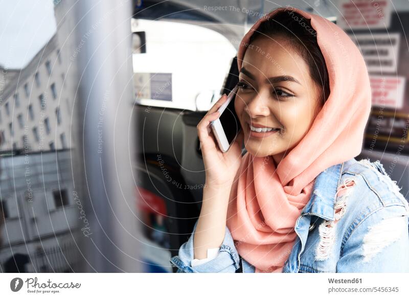 Großbritannien, England, London, junge Frau mit Hijab am Telefon im Taxi Handy Mobiltelefon Handies Handys Mobiltelefone muslimisch Moslem Muslim Taxis Taxen