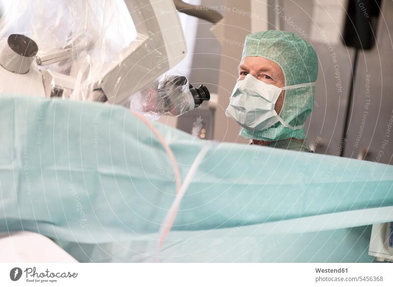 Neurochirurg mit Mikroskop im Operationssaal OP Operationen operieren Chirurgie Arzt Doktoren Ärzte Behandlung Krankenbehandlung Krankenbehandlungen