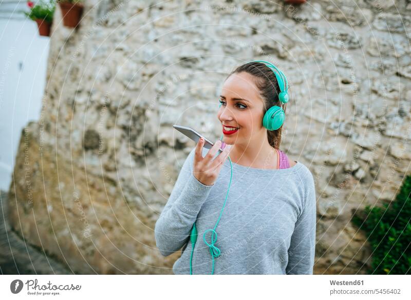 Junge Frau mit Kopfhörer, die eine Sprachnachricht sendet Kopfhoerer sprechen reden Smartphone iPhone Smartphones jung weiblich Frauen Musik hören Handy