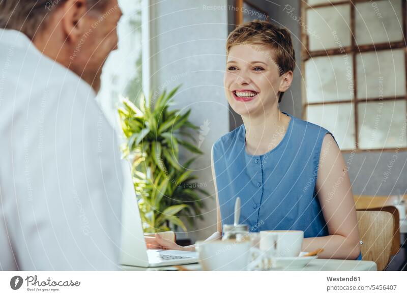 Geschäftsmann und Geschäftsfrau treffen sich in einem Cafe Meeting Business Meeting Kaffeehaus Bistro Cafes Café Cafés Kaffeehäuser sprechen reden lächeln