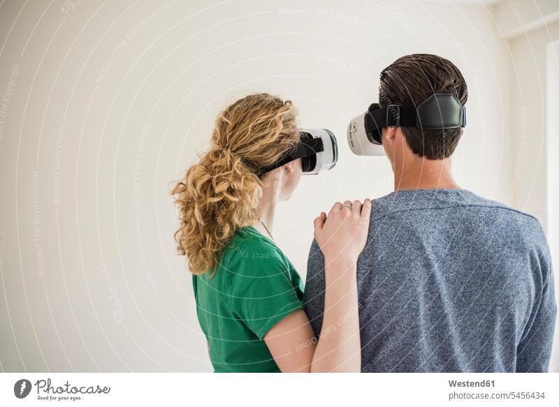 Junges Paar in leerer Wohnung mit VR-Brille Pärchen Paare Partnerschaft Virtual Reality Brille Virtual-Reality-Brille Virtual Reality-Brille VR Brille wohnen
