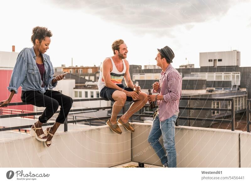 Drei Freunde treffen sich auf einer Party auf dem Dach feiern Parties Partys Spaß Spass Späße spassig Spässe spaßig trinken Dachterrasse Dachterrassen Bier