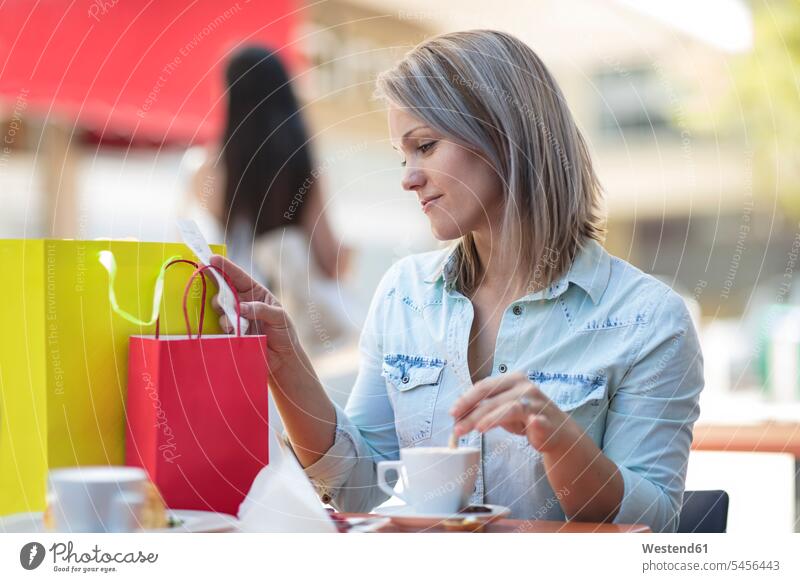 Frau mit Einkaufstaschen in einem Strassencafé bei der Kontrolle der Rechnung Shopping einkaufen shoppen Cafe Kaffeehaus Bistro Cafes Café Cafés Kaffeehäuser
