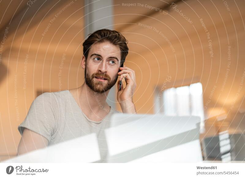 Porträt eines jungen Mannes am Telefon in einem Loft telefonieren anrufen Anruf telephonieren Männer männlich Telefon benutzen Erwachsener erwachsen Mensch