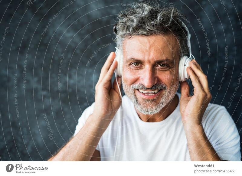 Reifer Mann lächelt, trägt Kopfhörer Musik Kopfhoerer lächeln zuhören zuhörend reifer Mann reife Männer Portrait Porträts Portraits männlich Erwachsener