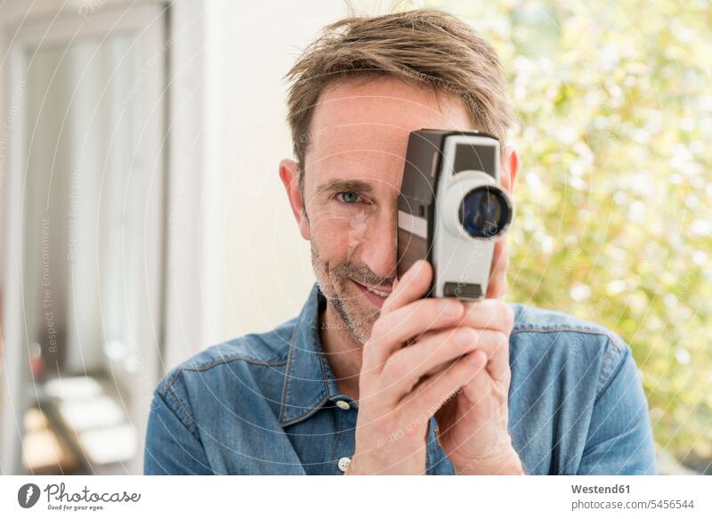 Porträt eines lächelnden Mannes mit Filmkamera auf den Betrachter blickend Filmkameras Männer männlich Erwachsener erwachsen Mensch Menschen Leute People