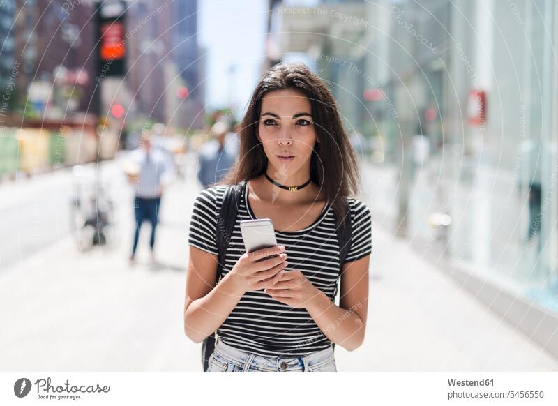 USA, New York City, junge Frau mit Handy in Manhattan weiblich Frauen Mobiltelefon Handies Handys Mobiltelefone Erwachsener erwachsen Mensch Menschen Leute