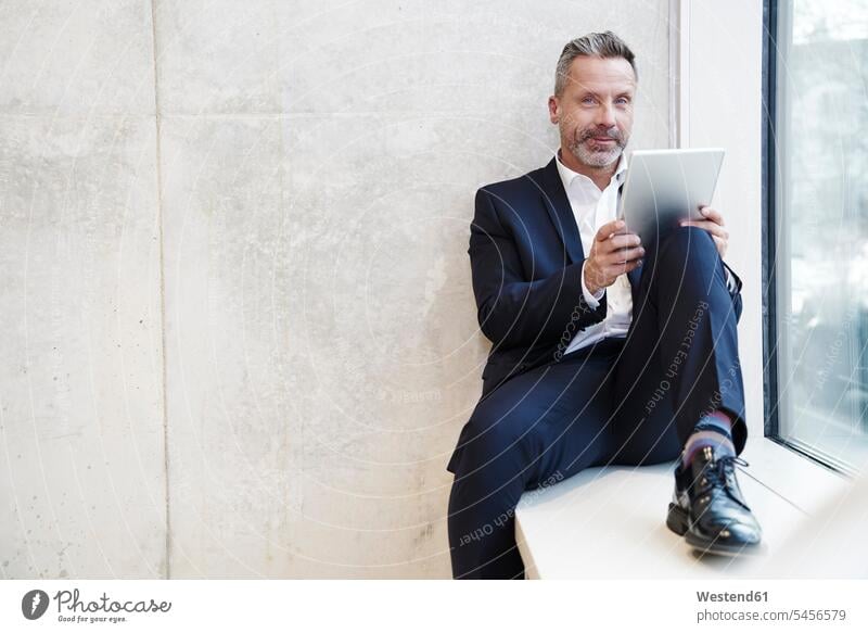 Porträt eines lächelnden Geschäftsmannes mit Tablette am Fenster Businessmann Businessmänner Geschäftsmänner Tablet Computer Tablet-PC Tablet PC iPad