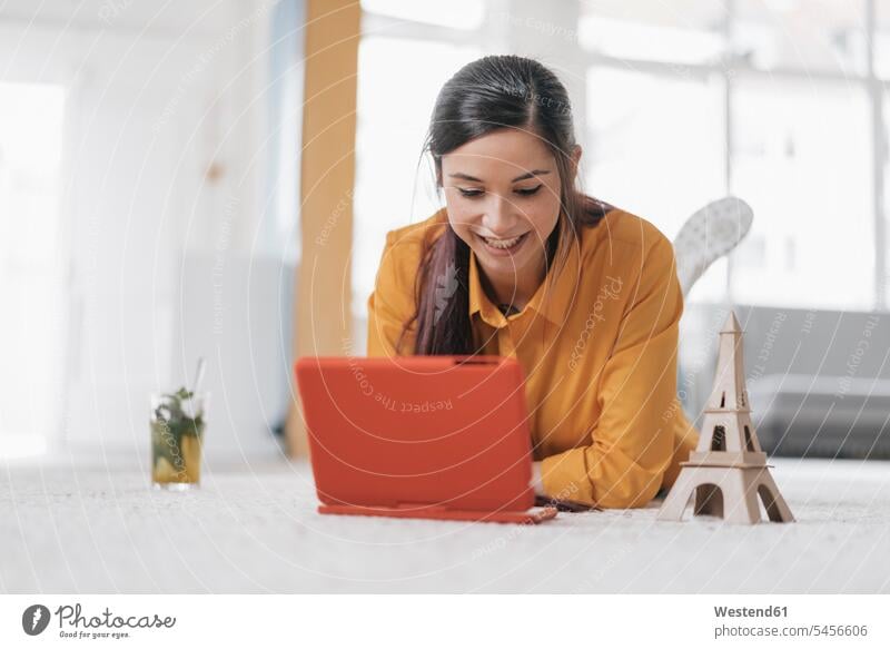 Junge Frau mit Modell des Eiffelturms plant Reise nach Paris weiblich Frauen Buchung buchen liegen liegend liegt Teppich Teppiche Laptop Notebook Laptops