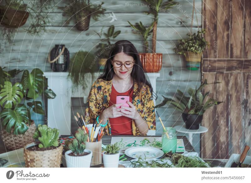 Junge Frau fotografiert gemalte Pflanzen mit ihrem Smartphone Aquarell iPhone Smartphones Handy Mobiltelefon Handies Handys Mobiltelefone fotografieren